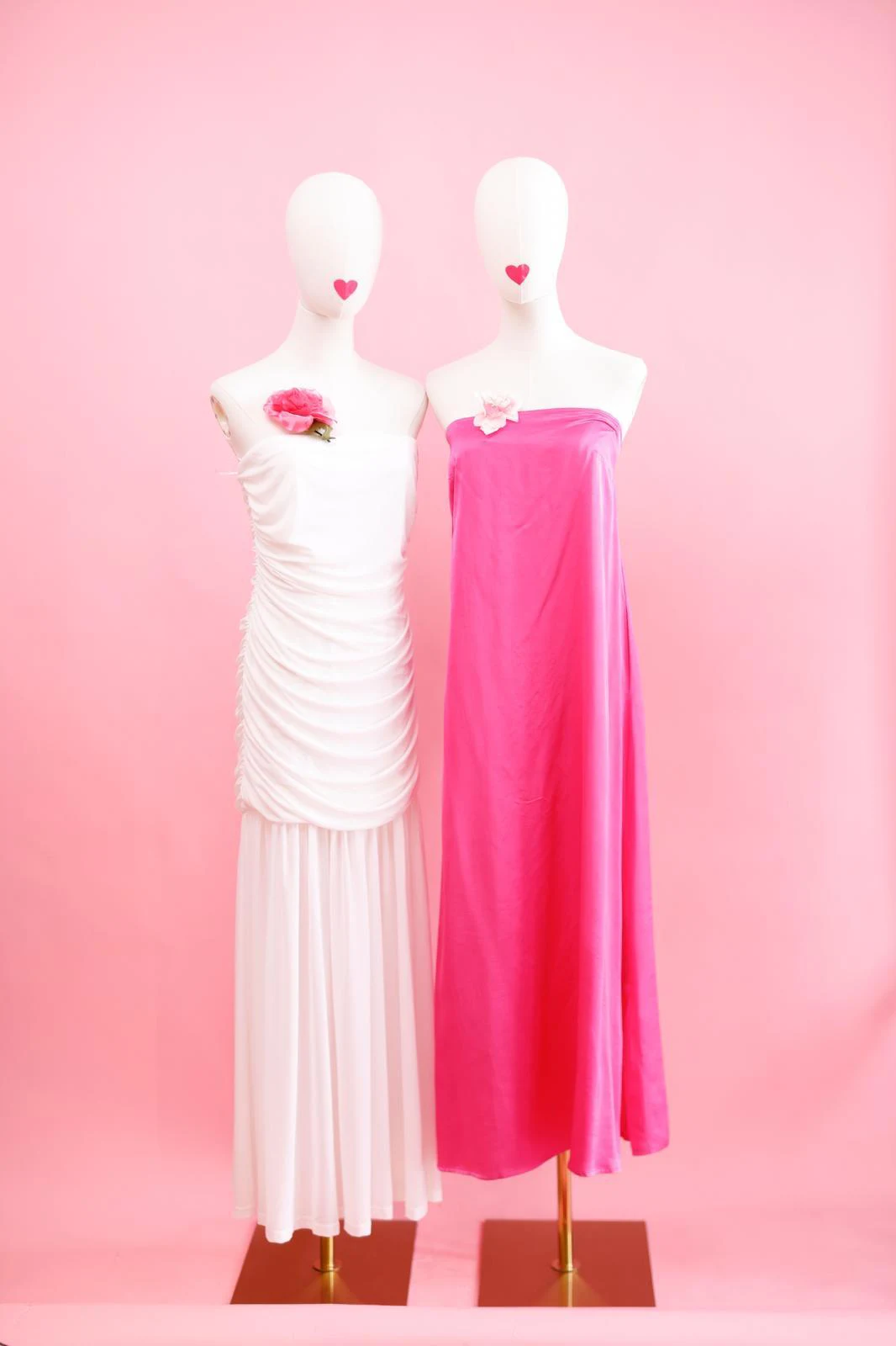 Zwei Kleider in Weiß und Pink vor rosa Wand